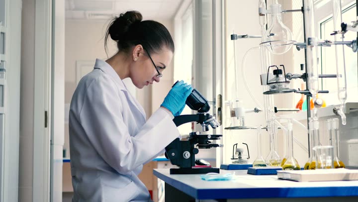 A scientist in a lab coat at a microscope