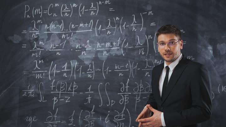 A teacher explaining equations at a blackboard